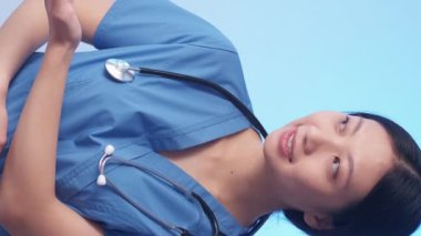 Dikey video. Tıbbi asistanım. Kadın doktor. Neşeli sakin terapist yan gülümseme dikkat edin üniforma servisi mavi fotokopi alanı arka planı.