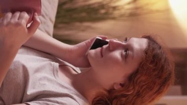 Dikey video. Mobil konuşma. Telefon görüşmesi. Neşeli milenyum kadını arkadaş canlısı kablosuz iletişim aygıtı ev tatili rahatı rahatlayın bardak sıcak çay.