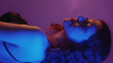 Dikey video. Flört eden kadın. Göz kırpma ifadesi. Neon gece portresi. Şehvetli kadın randevusu partisi. Geri dön..