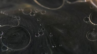 Yağ kabarcıkları. Parıldayan mürekkep. Odaklanamayan siyah altın rengi yüzen yarı şeffaf damlalar parlak parçacıklar parlayan emülsiyon akış hareketi soyut sanat arka planı.