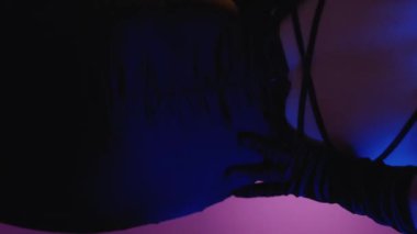 Dikey video. Dans eden kadın. Flört ifadesi. Şehvetli kadın, yumuşak, kaliteli, akşam ipek elbisesi açık, oyuncu, mor, neon ışık gradyan arka plan..