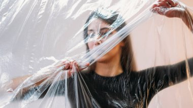 Modern hayatı, modern toplumun kısıtlamalarını sembolize etmek için plastik ambalaja dolanmış kavramsal sanat sergisi kadınlarıyla keşfedin..