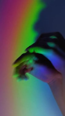 Dikey video. Gökkuşağı elleri. LGBT hakları. Cinsiyet bozukluğu. Boş alan arkaplanı üzerinde parlak renk gradyan ışık ile odaksız parlayan kadın avuçlar.