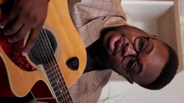 Dikey video. Müzik öğretmeni. Gitar dersi. Takım elbise giymiş mutlu dost canlısı uzman bir eğitimci sanat okulunda kapalı alanda şarkı akorlarını açıklıyor..