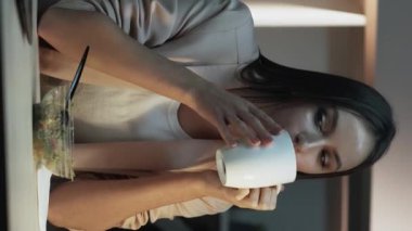 Dikey video. Ofis yemeği. Çoklu görev yöneticisi. Mutlu işkolik kadın yemek molasında iş yapıyor. Telefonlara cevap veren bilgisayarlar yiyor..