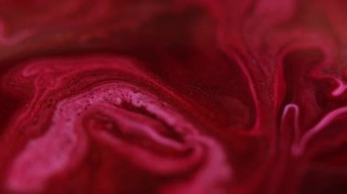 Parlak sıvı karışımı. Boya dökülmüş. Odaklanmamış kırmızı pembe renk parıldayan parçacıklar sıvı emülsiyon akış hareketini soyut sanat arkaplanı.