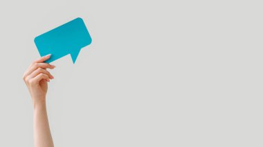 Konuşma balonu. Boş mesaj. Çevrimiçi sohbet. Nötr boş arkaplanda izole edilmiş metin için mavi diyalog simgesi tutan kadın eli.