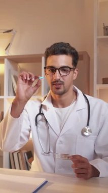 Dikey video. Vitamin reçetesi. Doktor randevusu. Modern klinikte masada oturan sağlıklı ilaç ve takviye maddelerine danışmanlık yapan zeki bir uzman..