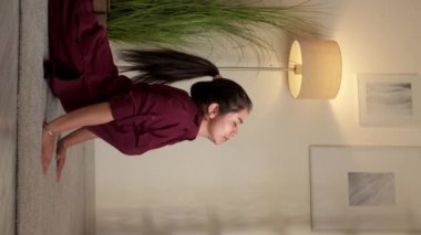 Dikey video. Yoga eğitimi. Evde spor salonu. Sağlıklı bir hobi. Sakin esnek kadın Bhujangasana kobrası oturma odasında uttana shishosana pozu veriyor..