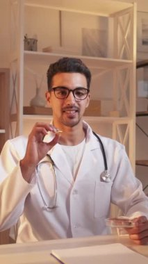 Dikey video. İlave haplar. Sağlık danışmanlığı. Doktor blog. İnternet kanalı için vitamin kompleksine danışmanlık yapan profesyonel tıp uzmanı çalışma masasında oturuyor..