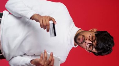 Dikey video. Banka dolandırıcılığı. Çevrimiçi dolandırıcılık. Elektronik ödeme güvenliği. Sinirli bir adam kredi kartı cep telefonu uygulaması kullanıyor..
