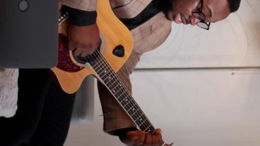 Dikey video. Müzisyen blogu. Gitar çevrimiçi kursu. Akort dersi. Profesyonel erkek, evdeki internet dizüstü bilgisayar dersinde oyun dersi veriyor..