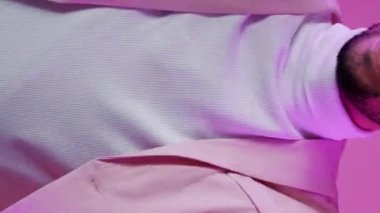 Dikey video. Disko partisi. Müzik eğlenceli. Özgürlük sevinci. Mor renkli, neon ışıklı, kendine güvenen, gözlüklü, rahat, pembe üzerinde yalnız dans eden adam..