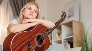 Müzik ilhamı. Hayalperest kadın. Romantik bir ruh hali. Gülümseyen bayan oyuncu dizlerinin üzerinde gitar tutuyor..