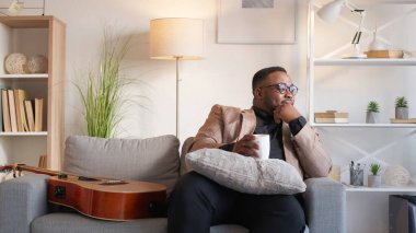 Kahve gevşedi. Sıcak bir mola. Ev tatili. Mutlu hayalperest adam çay içiyor. Oturma odasında rahat koltuğun üzerinde dinleniyor..