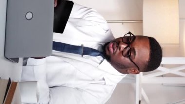 Dikey video. Tıp profesörü. Radyoloji teşhisi. Sağlık hizmetleri uzmanlığı. Cep telefonu. Ciddi derecede zeki bir doktor. Bilgisayarda röntgen taraması yapıyor. Klinik masasında telefonla konuşuyor..