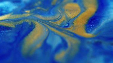 Parlak sıvı karışımı. Boya dökülmüş. Odaklanmamış mavi altın rengi parıldayan partiküller sıvı emülsiyon akış hareketini soyut sanat arkaplanı.