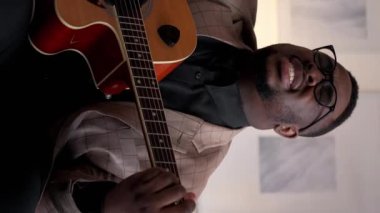 Dikey video. Müzik ilhamı. Gitarist eğlencesi. Şarkı performansı. Evde akustik enstrümanla şarkı söyleyen yetenekli duygusal adam..