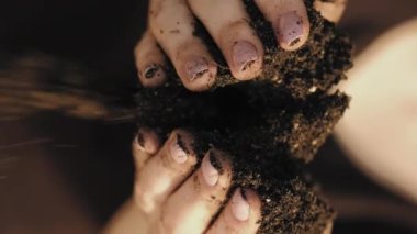 Dikey video. Doğal gübre. Bir avuç dolusu. Ekoloji günü. Fotokopi alanının arka planına taze toprak döken kadın parmaklar.