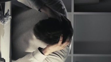 Dikey video. Proje başarısız. İşyeri harabesi. Kariyer krizi. Gece ağrısı. Sinirli düşünceli, canı sıkkın bir çalışan, karanlık ofis odasında baş ağrısından muzdarip..