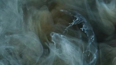 Işıltılı sis girdabı. Mürekkep su sıçratır. Odaklanmamış mavi altın rengi ışıldayan parçacıklar desen duman girdap hareketi soyut sanat arkaplanı.