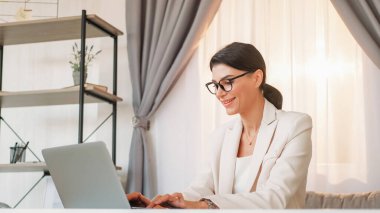 Çalışan kadın. Sanal iletişim. Dijital teknoloji. Zarif takım elbiseli olumlu bir bayan. Laptop yazıyor. Çalışma masasında, aydınlık odada..