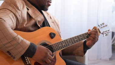 Gitar sanatçısı. Müzik alıştırması. Tanınmayan yetenekli erkek elleri telli çalgılarla şarkı akorları çalıyor evde yaratıcı aktivitelerin keyfini çıkarıyor..