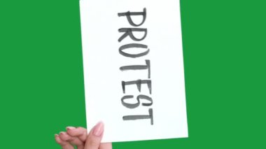 Dikey video. Protesto işareti. Vuruş levhası. Yeşil renkli anahtar boş arkaplan üzerinde izole edilmiş harf metnini gösteren kadın eli.