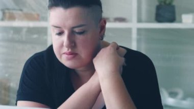 Depresyon izolasyonu. Üzücü bir hayal kırıklığı. Nostaljik aşırı kilolu kadın melankolik bir şekilde iç çekiyor elleri kavuşturup oturma odasını kopyalıyor..