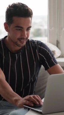 Dikey video. Mesafe çalışması. Bilgisayar teknolojisi. Evde oturan modern dizüstü bilgisayara odaklanmış serbest programcı geliştirici..