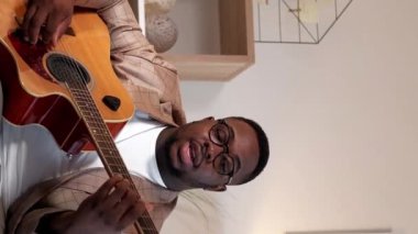 Dikey video. Müzik blogcusu. Gitar kursu. Uzaktan eğitim. Evdeki sanal toplantıda enstrüman dersi veren adam akorları açıklıyor..