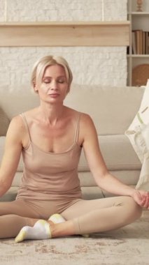 Dikey video. Nefes meditasyonu. Uyum sabahı. Huzurlu, rahat bir kadın, Lotus 'ta poz verip, Nirvana' nın tadını çıkarıyor..