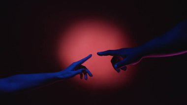 İnsan dayanışması. Etnik eşitlik. Çoklu kültürel çeşitlilik. Erkek ve kadın parmaklarını kırmızı spot ışığı arkaplanındaki yaratıcı reklama dokunduruyor..