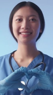 Dikey video. Dost canlısı doktor. Kalp hareketi. Destekleyici, neşeli, el ele tutuşan kadın sağlık hizmetleri gönüllüsü sembolü sevgiyi gösteriyor..