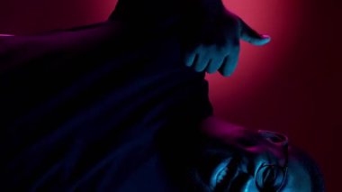 Dikey video. Jest gibi. Seçim onayı. Olumlu geri bildirim. Mutlu gülümseyen adam, kırmızı neon ışıklı arka planda başparmağınla tavsiye işareti yap..