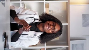 Dikey video. Destekleyici doktor. Tıbbi başarı. Sağlık sigortası kutlaması. Mutlu kadın pratisyen hekim, masa başı hastanesinde el çırpıyor..