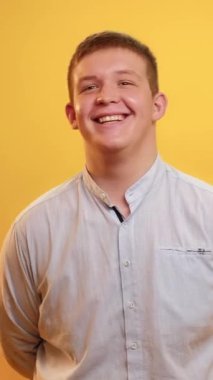 Dikey video. Vücut pozitifliği. Harika bir ruh hali. Kendine güvenen insanlar. Mutlu tombul, kilolu, kızıl saçlı, dişleriyle gülümseyen, sarıya izole edilmiş, iyimser poz veren adam..