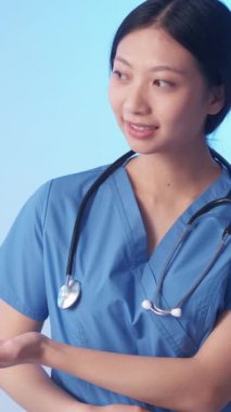 Dikey video. Tıbbi asistanım. Kadın doktor. Neşeli sakin terapist yan gülümseme dikkat edin üniforma servisi mavi fotokopi alanı arka planı.