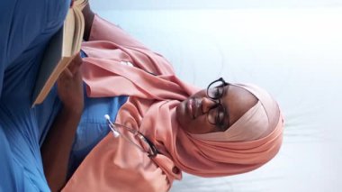 Dikey video. Tıp eğitimi almış. Hastalık araştırması. Klinikte profesyonel sağlık hizmetleri kitabı okuyan düşünceli stajyer doktor öğrenci..