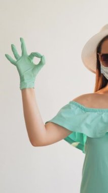 Dikey video. Salgın hazır. Virüs koruması. Maskeli bir kız. Tatil eldiveni takıyor. Güneş gözlüğü sinyal veriyor..