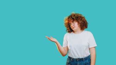 Memnun olmayan kadın, mavi boş arkaplanda izole edilmiş şüpheli ifadeler sergileyerek hayal kırıklığına uğradı..