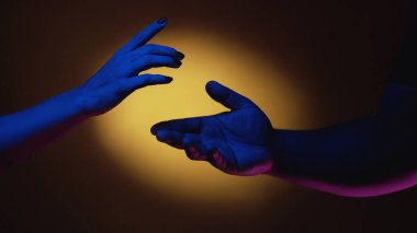 Aşk çeşitliliği. Eşitlik desteği. Çok ırklı bir çift. Kadın erkek el ele tutuşuyor uluslararası romantik birliktelik açık sarı ışıkla karanlık arka planda.