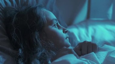 Çocuk korkusu. Gece paniği. Kötü uyku. Korkmuş küçük kız battaniyenin altında saklanıyor. Yatakta tek başına, mavi ay ışığıyla karanlık bir evde yatıyor..
