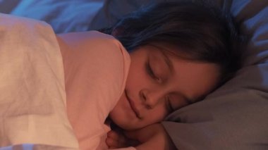 Uyku alışkanlığı. Anne şefkati. Huzur içinde uyu. Ebeveyn bakımı. Kadın elleri battaniyeyle örtülmüş. Sevimli küçük bir kızı okşuyor. Geceleri rahat yatak odasında uyuyor..