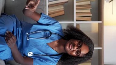 Dikey video. Hastalık zaferi. Sağlık hizmeti başarısı. Tıbbi kazanç jesti. İki parmağı olan neşeli kadın doktor klinikteki kanepede tedavi olduğu için mutlu..