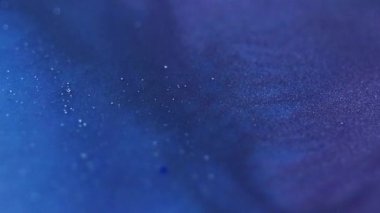 Işıldayan akış. Parıltı hareketi. Odaklanmamış mavi mor renkli parlak boya parçacıkları dokusu soyut büyülü sanat arkaplanı karışımı.