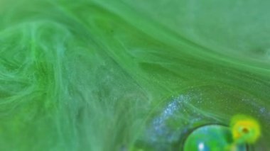 Boya dökülmüş. Parıldayan mürekkep. Yağ damlası. Odaklanamayan yeşil mavi renk sızıntısı parlak şeffaf kabarcıklar parıltılı sıvı soyut sanat arkaplanı sızdırıyor.