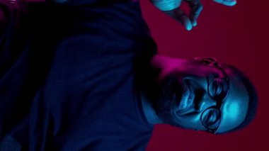 Dikey video. Tamam jest. Güzel seçim. Memnuniyet duyan neşeli adam, aferin sana. Kırmızı bordo arka planda izole edilmiş neon ışığı imzala..