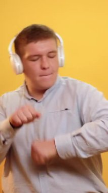 Dikey video. Müzik eğlenceli. DJ tarzı. Kulağa eğlenceli geliyor. Şişko şişman adam şarkılara geçiyor beyaz kulaklıklarla kışkırtıcı müzikler dinliyor sarıda tek başına dans ediyor..
