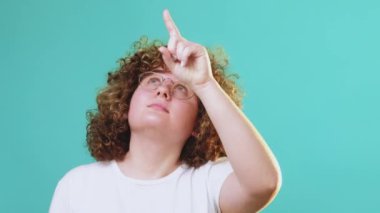 Meraklı öğrenci bilgi okuyor. Mavi fotokopi arkaplanda izole edilmiş parmak gösteren görünmez mesajı takip eden gözlüklü düşünceli akıllı kız..